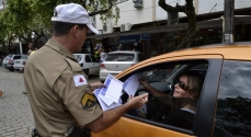 Sargento Waldecir entrega o panfleto a uma motorista durante a blitz