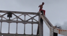 O preso no alto da estrutura da ponte metálica.
