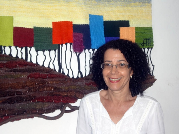 A artista e tecel&atilde; Alcione Martins &aacute; frente de um de seus tapetes