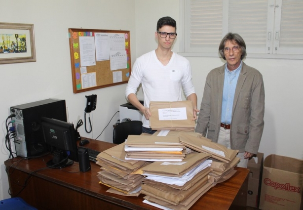 O Secretário de Cultura, Zeca Junqueira, à direita, com Gabriel Oliveira, funcionário da Secretaria e os projetos recebidos à frente, sobre a mesa