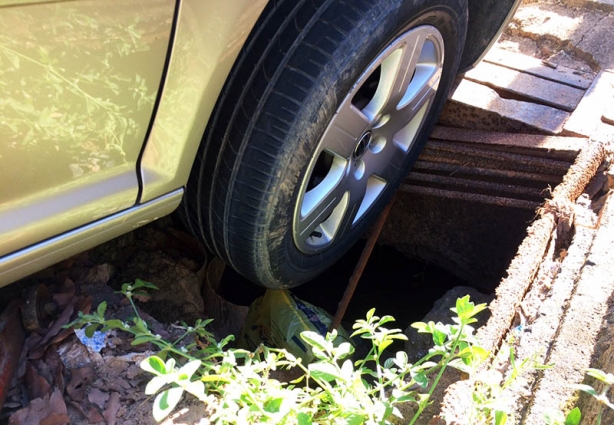 A roda direita dianteira do carro caiu na vala sem grade de proteção