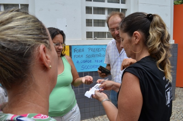 MIcaela, de blusa preta, com colegas, oferece um bilhete de rifa