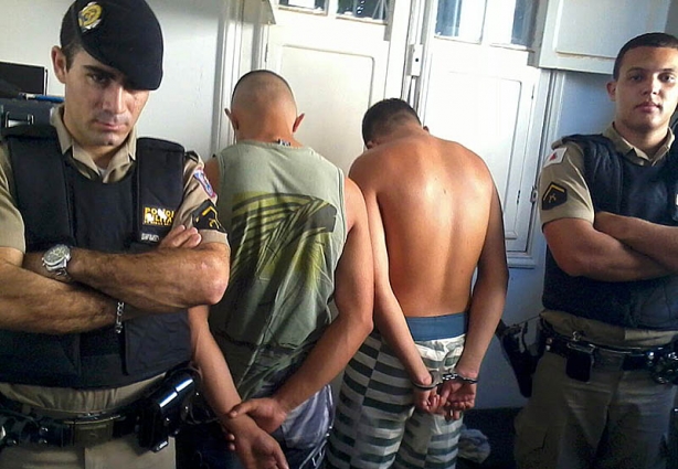 Os policiais responsáveis pela prisão dos dois suspeitos (de costas) de venderem drogas ilícitas