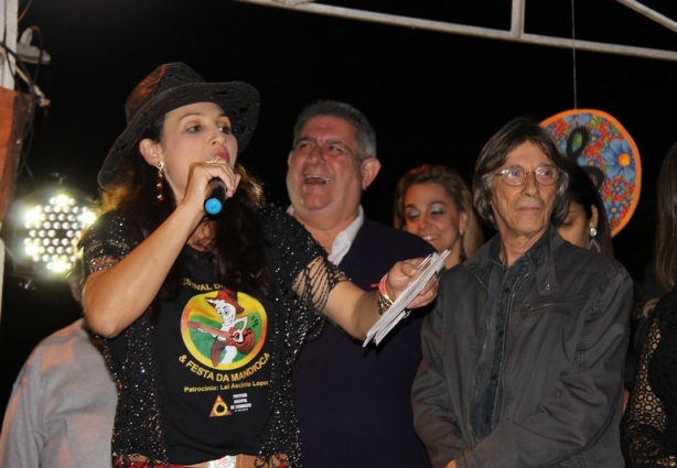 A animadora da festa, Raquel Braga, com o sorridente prefeito Cesinha atrás e o secretário de cultural, Zeca Junqueira