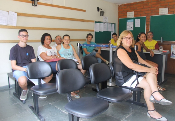 Eleitores de Santana de Cataguases aguardam para fazer o cadastramento eleitoral tendo ao fundo o chefe do Cartório