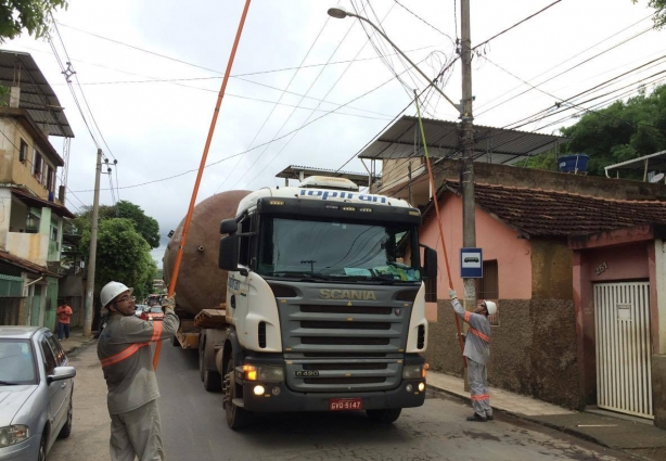 Funcionários da Energisa levantam os fios para o comboio passar pela Vila Minalda