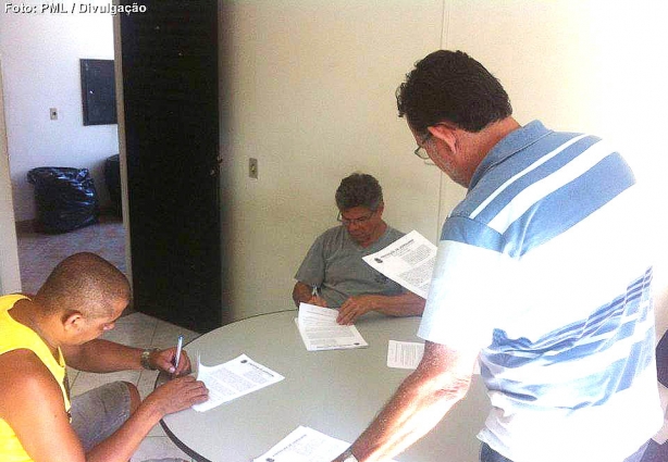 O prefeito José Roberto, sentado ao fundo, assina as outorgas, para os novos mototaxistas
