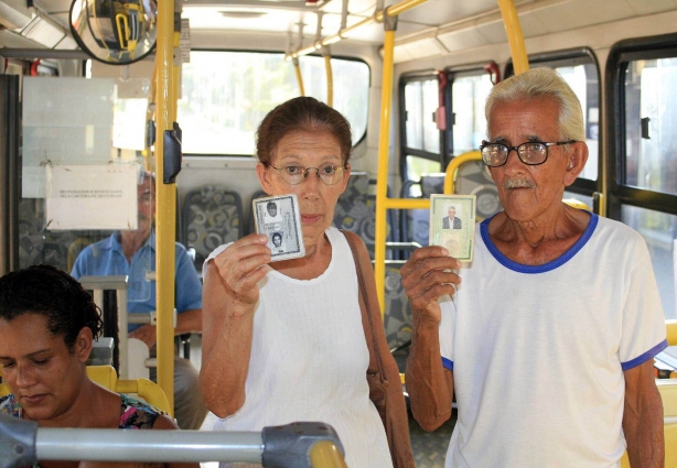 Beneficiados pela gratuidade, os dois usuários mostram suas respectivas carteiras dentro do ônibus urbano