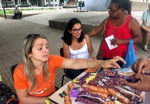 Tairises Roque entrega preservativos enquanto explica a importância da prevenção durante a relação sexual