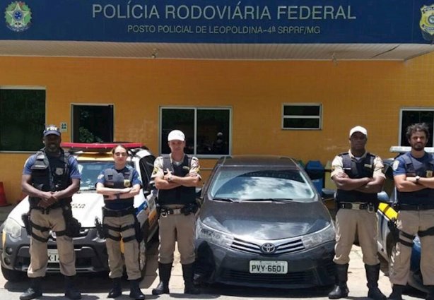 Os policiais rodoviários ao lado do carro apreendido