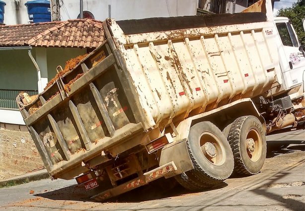 Roda traseira de caminhão afunda em buraco no meio da rua