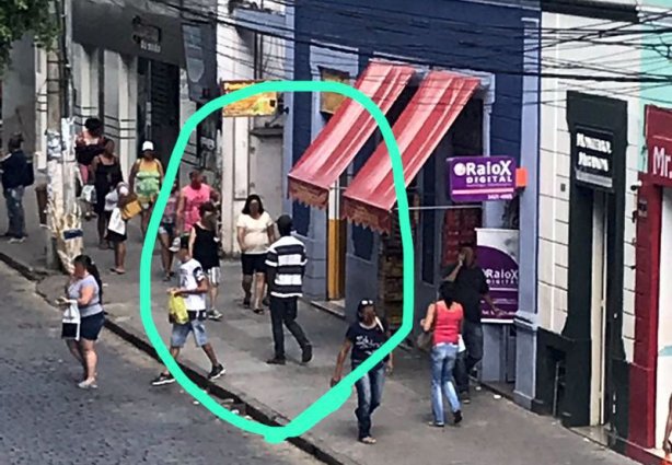 O homem de costas na foto usando camisa listrada de azul e calça jeans foi preso minutos depois pela Polícia Civil